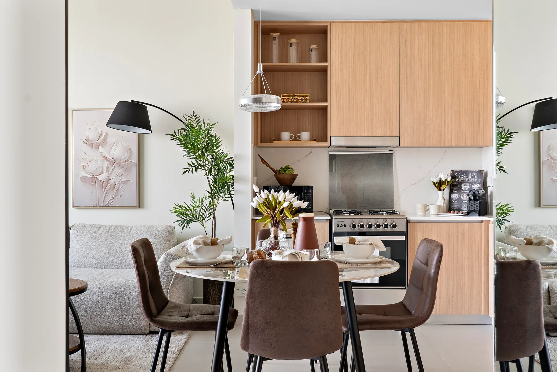 A dining area with a set table in front of a compact kitchen.