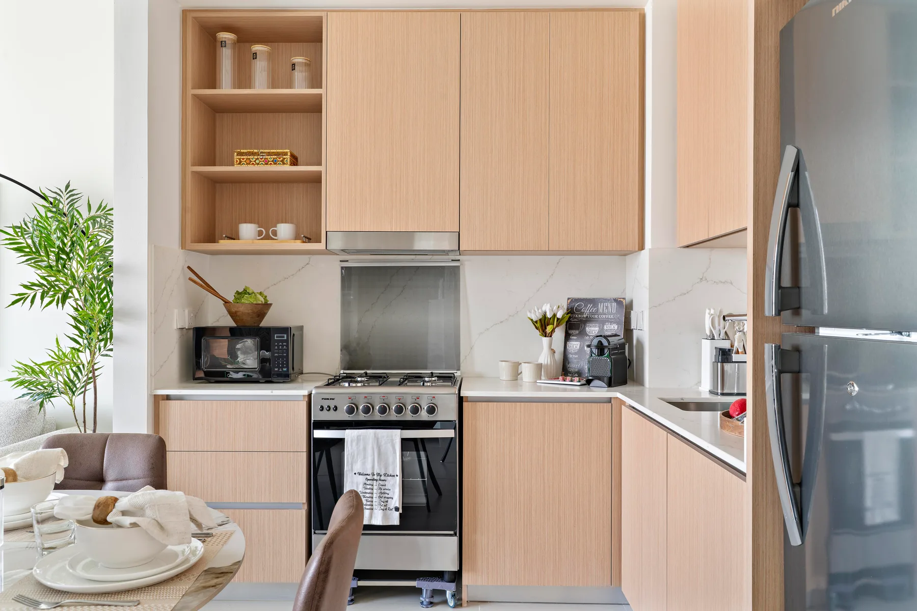 A bright kitchen with light wood cabinets, a stove, and a refrigerator.