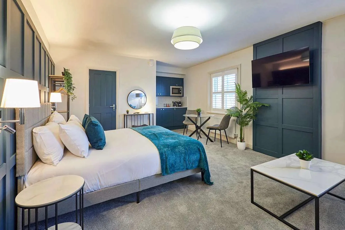 Dormitorio con cama, escritorio y televisor.