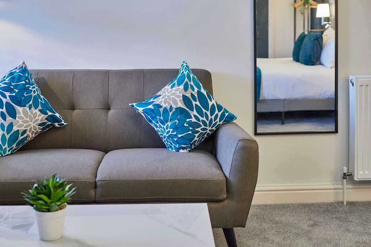 Una sala de estar con un sofá gris y cojines estampados azules.
