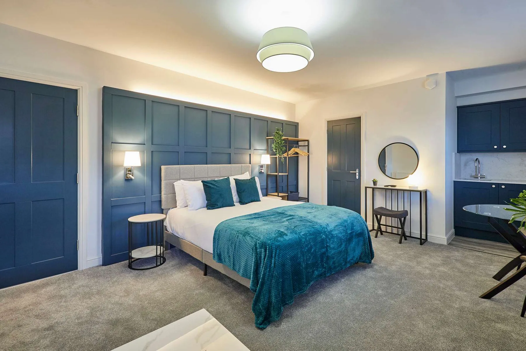 Un dormitorio con una cama vestida con ropa de cama blanca y verde azulado.