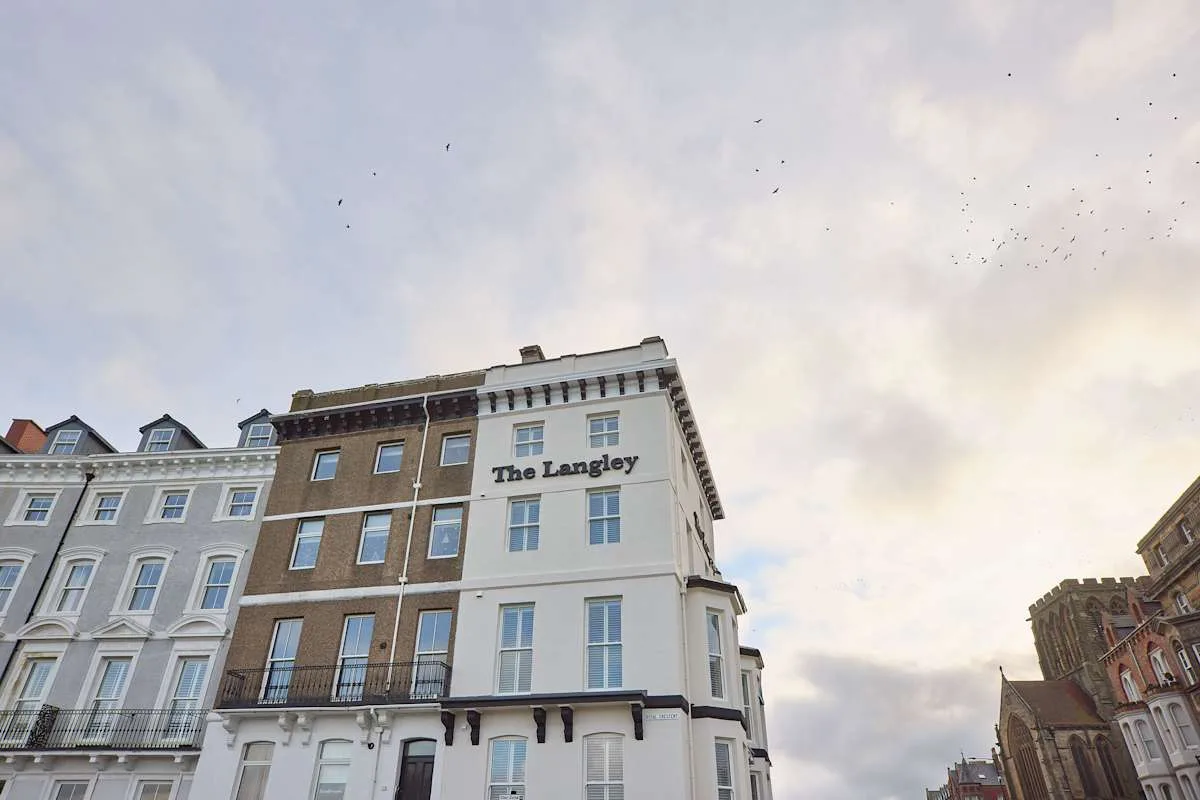 Un edificio de hotel con un letrero visible se alza bajo un cielo nublado.