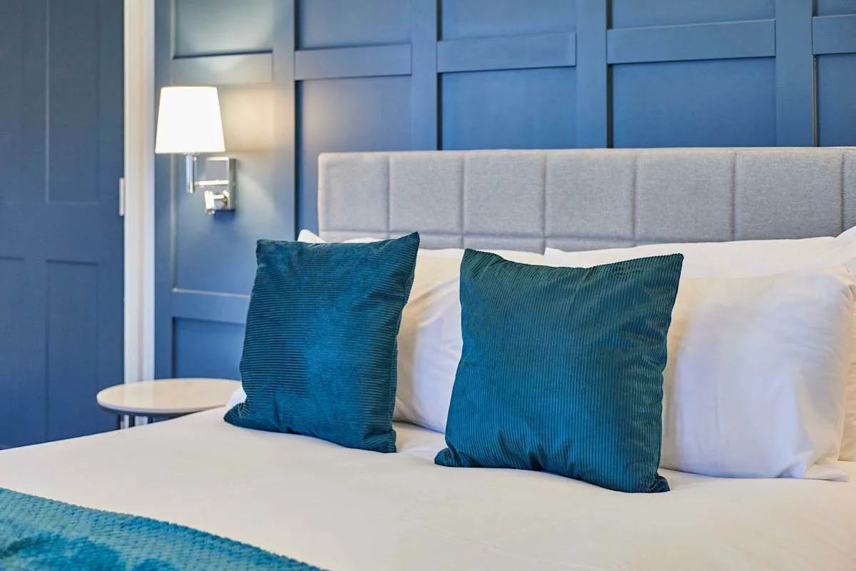 Un dormitorio con una cama tendida y cojines azules.