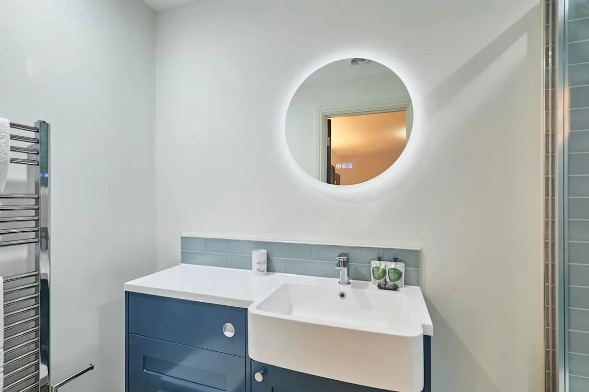 Un lavabo de baño está bajo un espejo redondo.