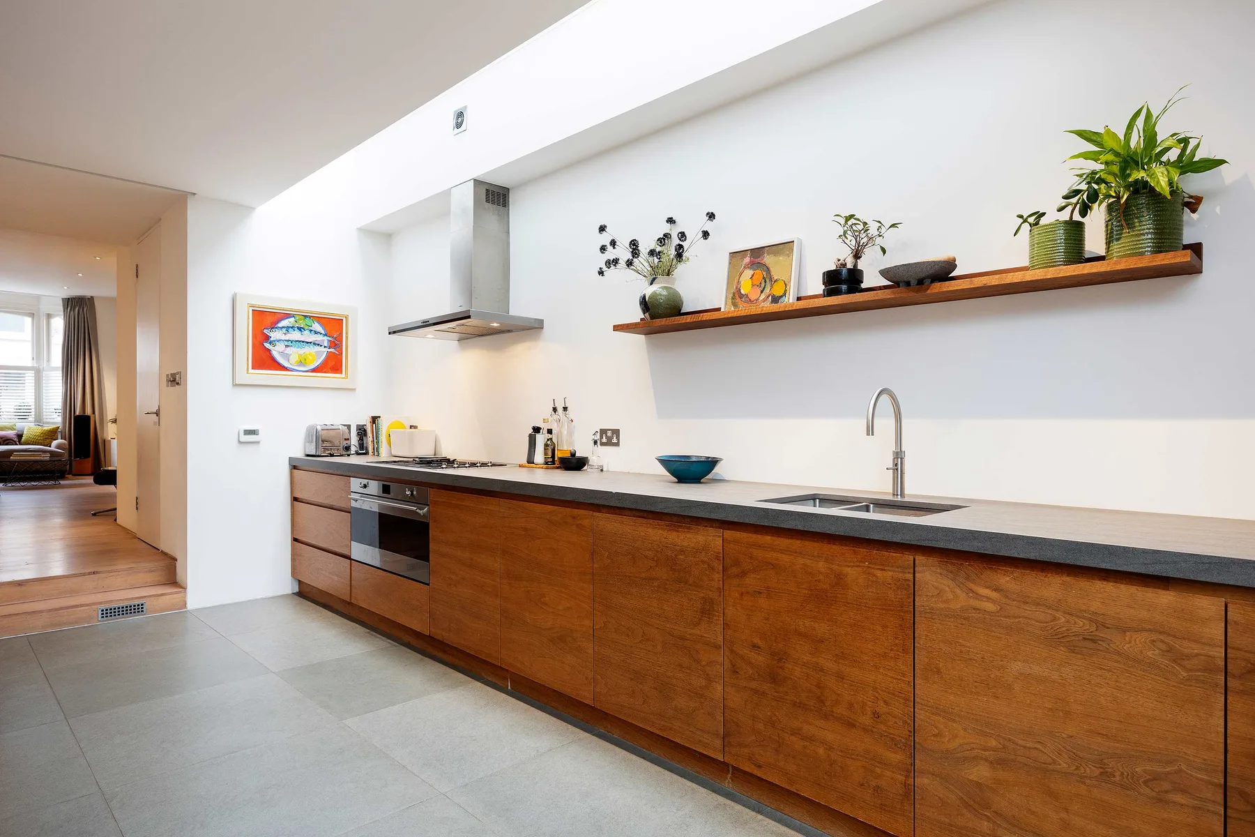 Una cocina moderna con gabinetes de madera, una encimera y un estante largo encima.