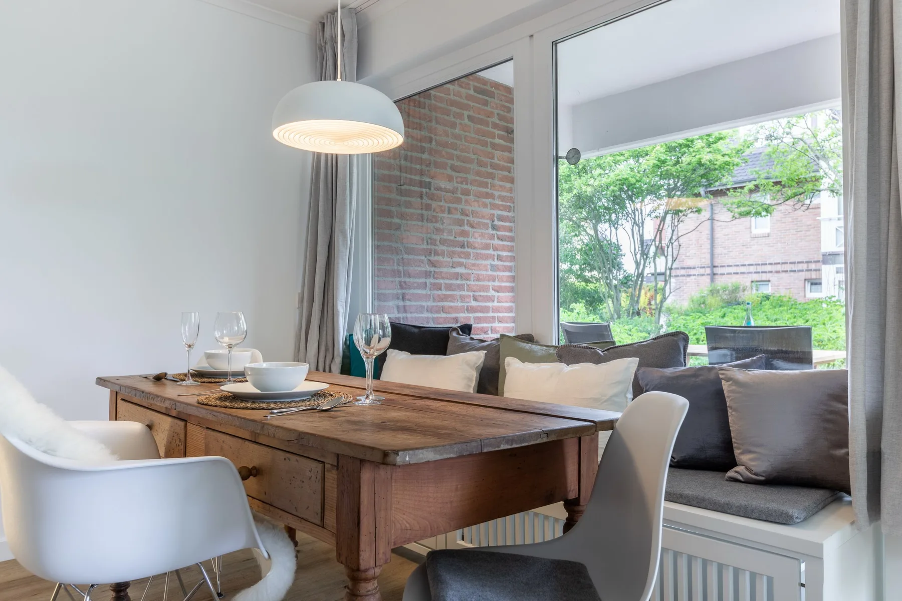 A dining area with a wooden table beside a window overlooking greenery.
