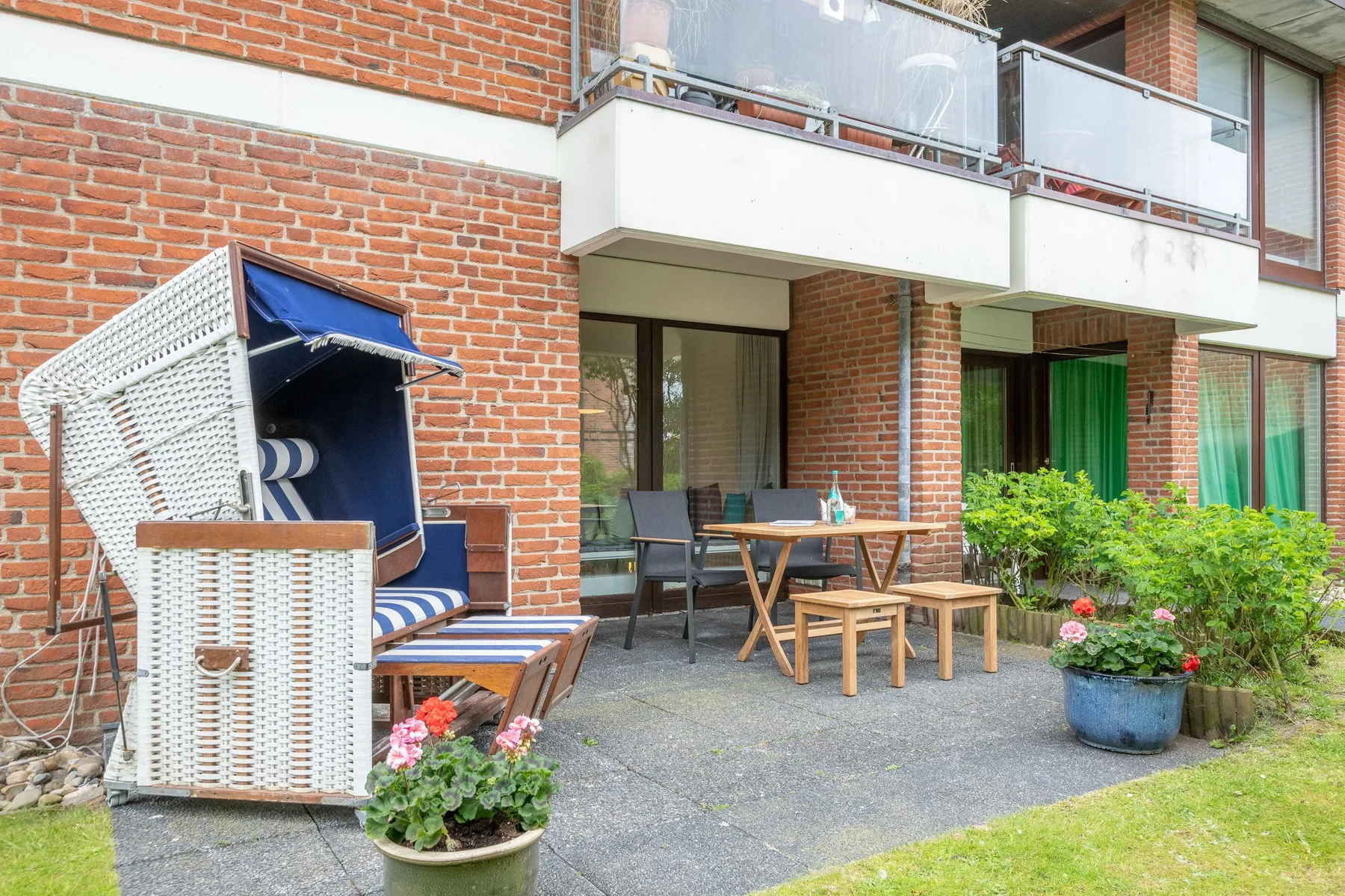 A patio with outdoor seating and a table beside a brick building.