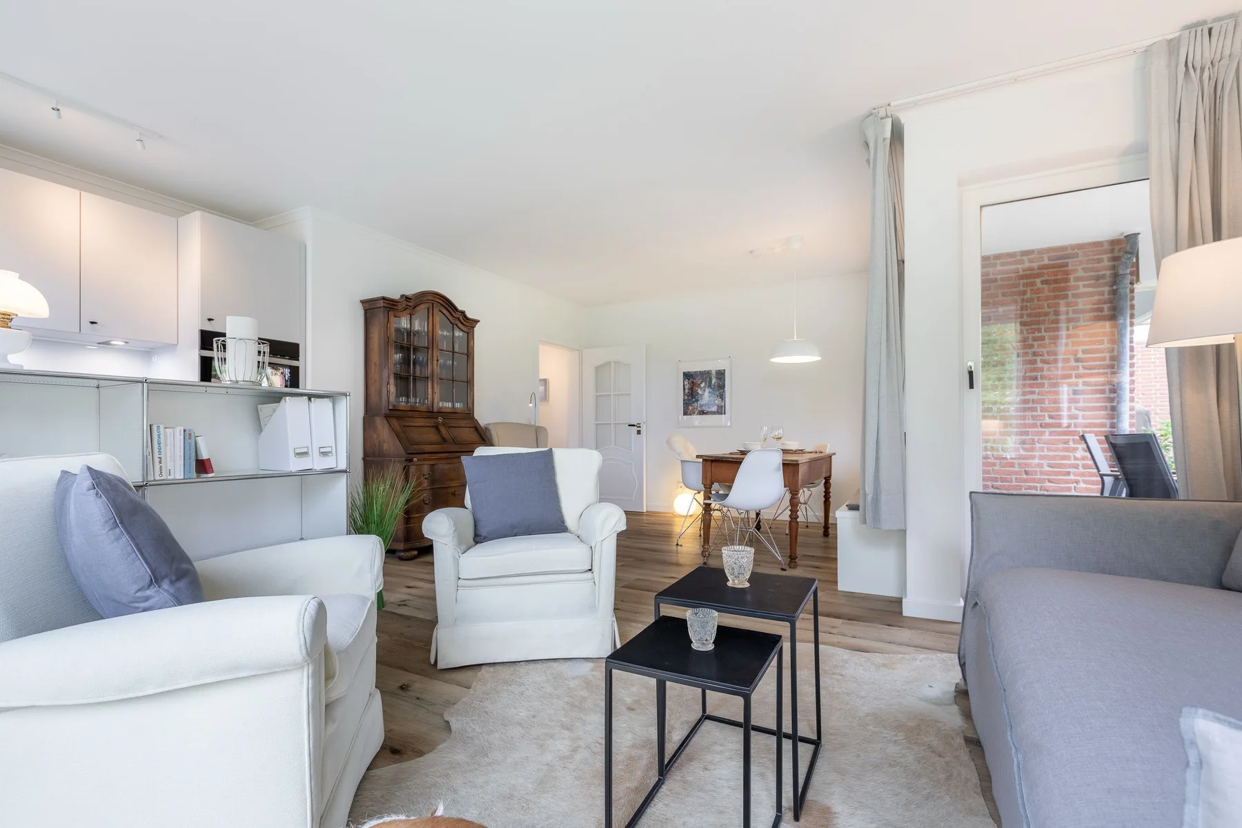 Bright living room with seating arranged around small tables and an adjoining dining area.