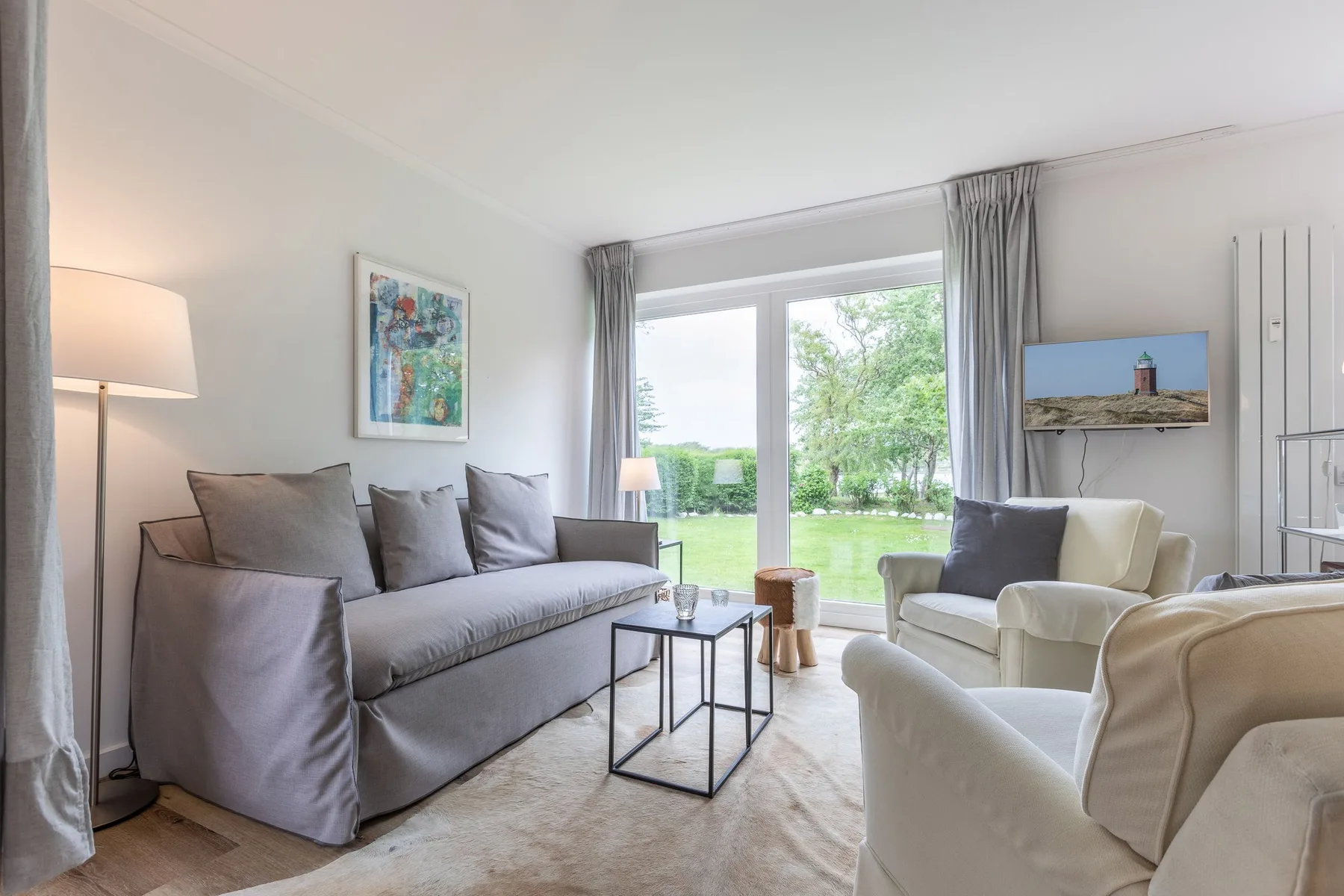 A bright living room with seating arranged around a glass coffee table.