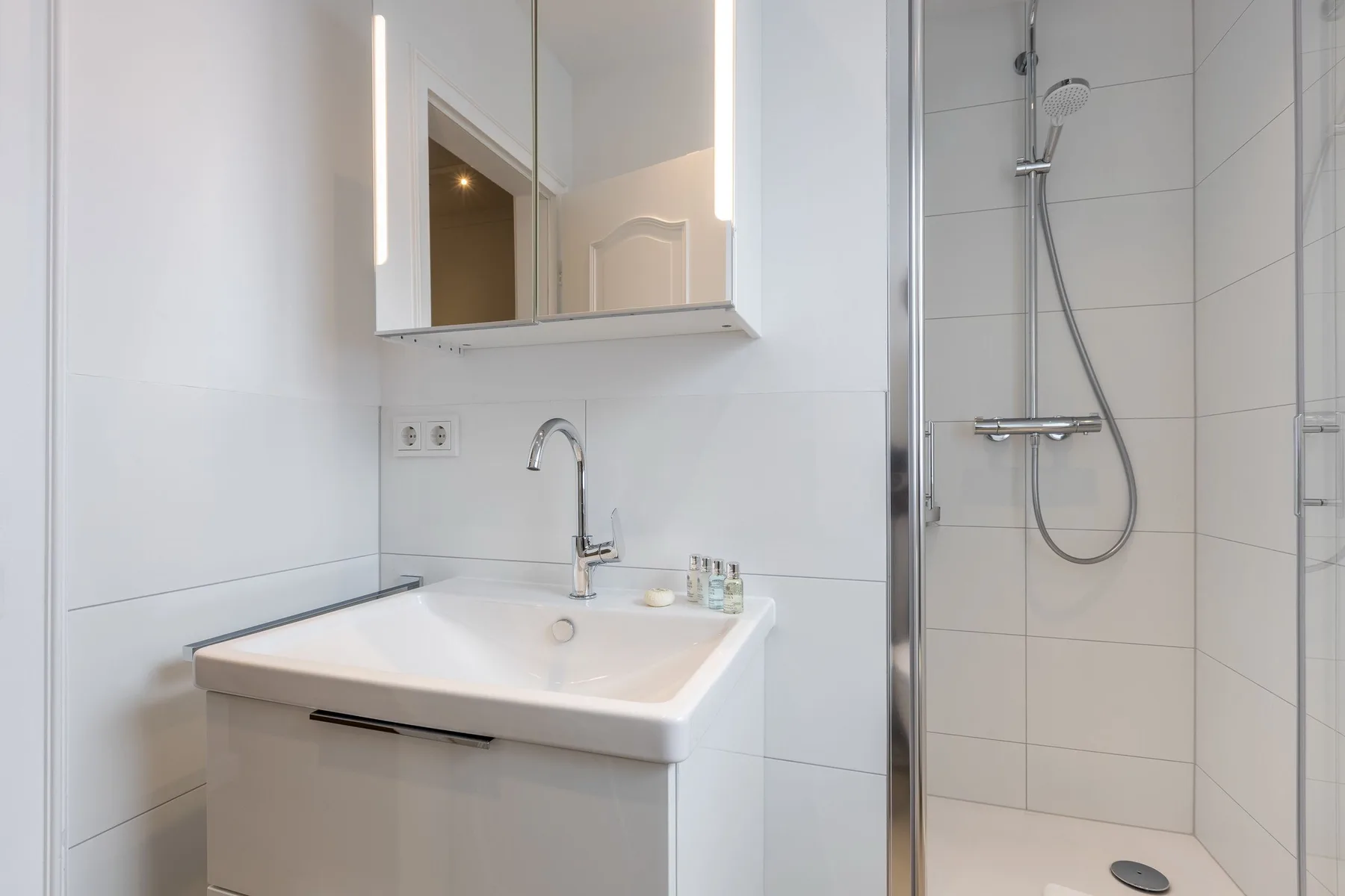 A bright bathroom with a sink and shower.