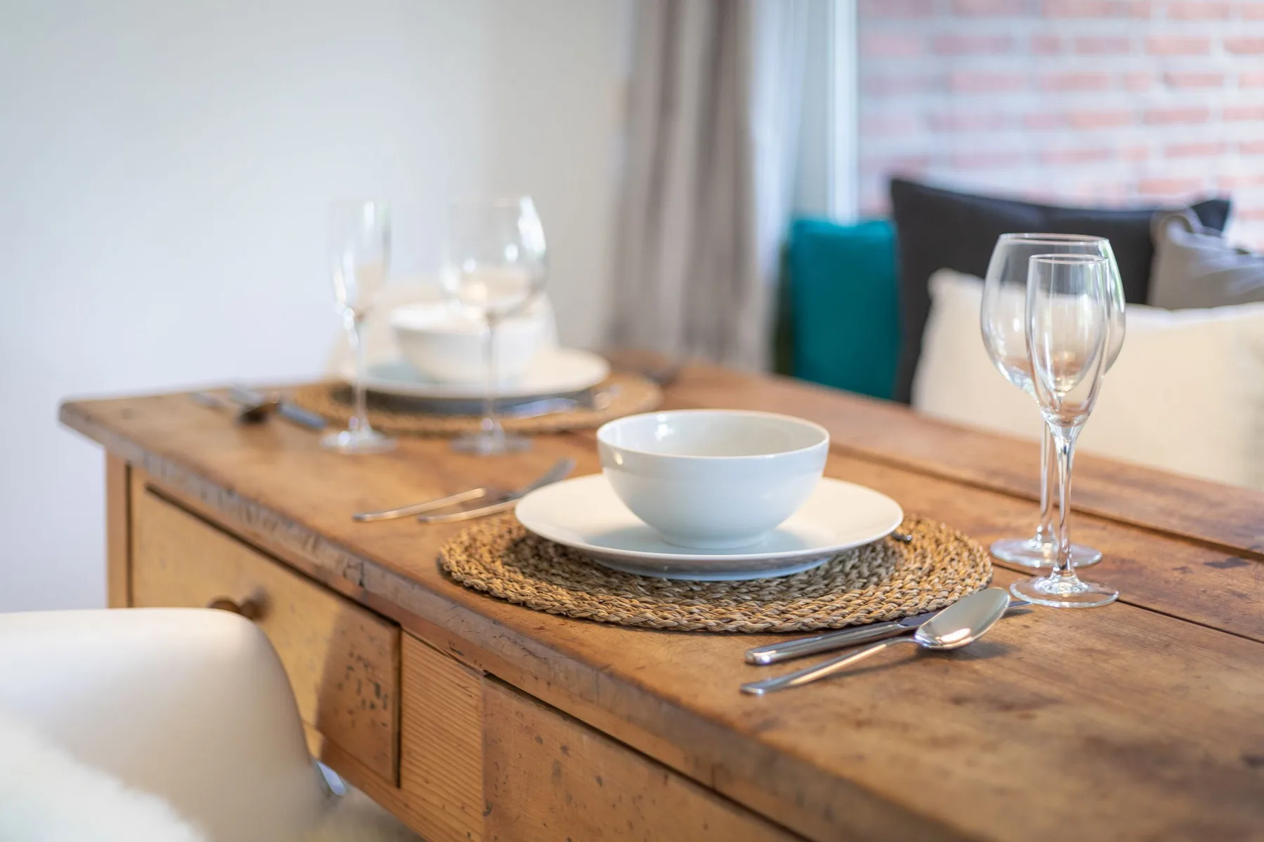 A dining table is set with plates, bowls, and wine glasses.