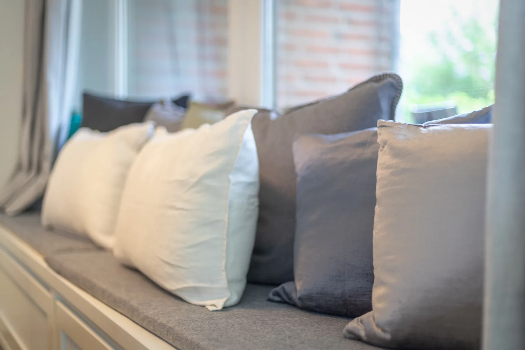 A window-side seating area has a row of white and gray cushions.