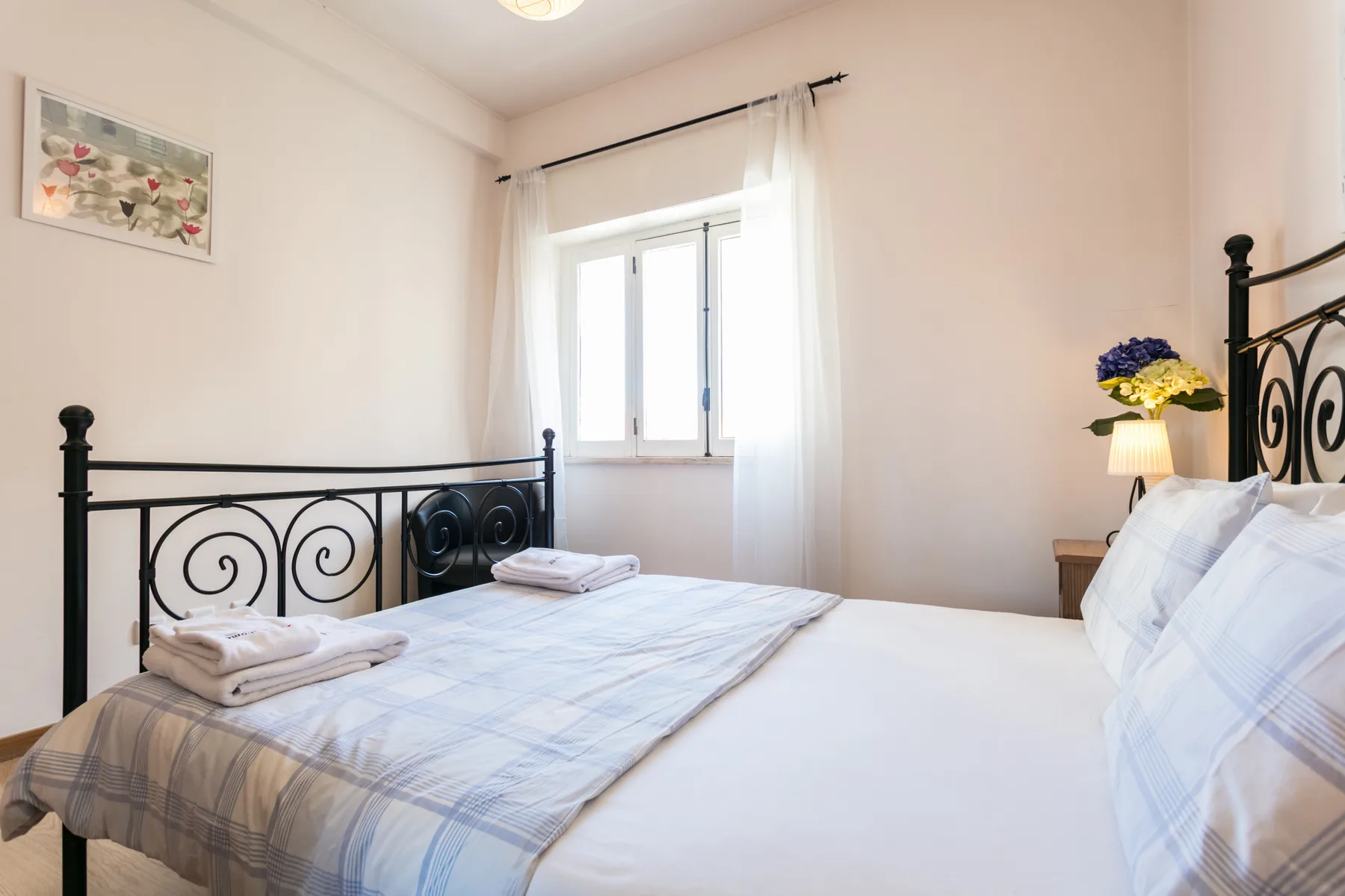Un dormitorio con una cama, toallas dobladas y una ventana con cortinas.