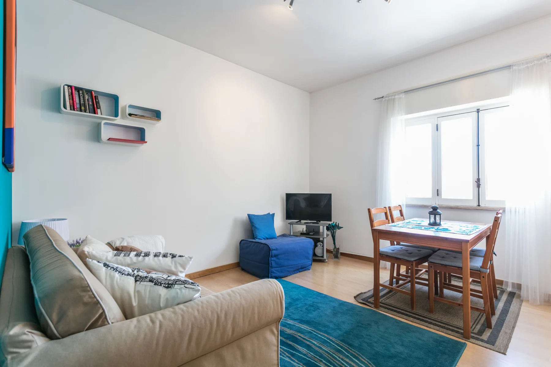 Sala de estar y comedor con asientos, un televisor y una mesa junto a la ventana.