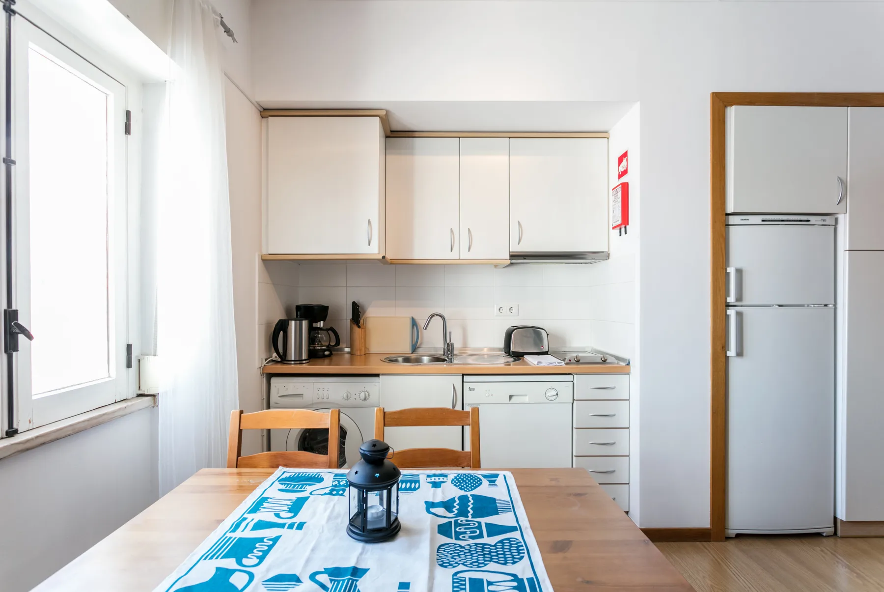 Una cocina luminosa con comedor y una mesa junto a una ventana grande.