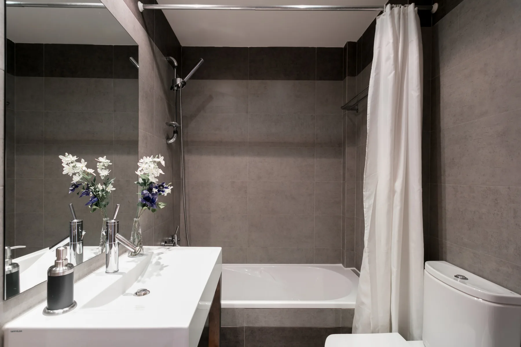 Un baño con lavabo, bañera y cortina de ducha blanca.