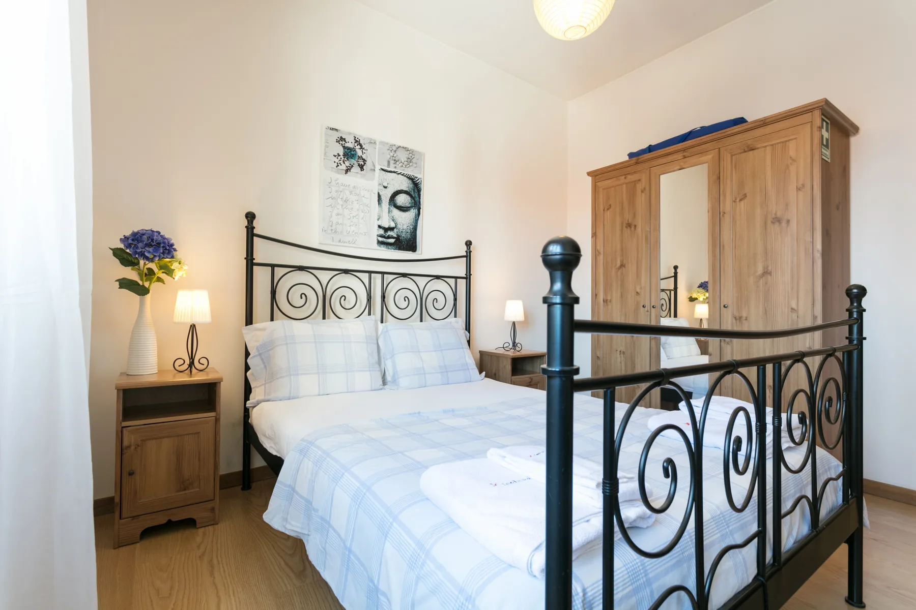 Un dormitorio con una cama con estructura metálica, mesillas y un armario de madera.