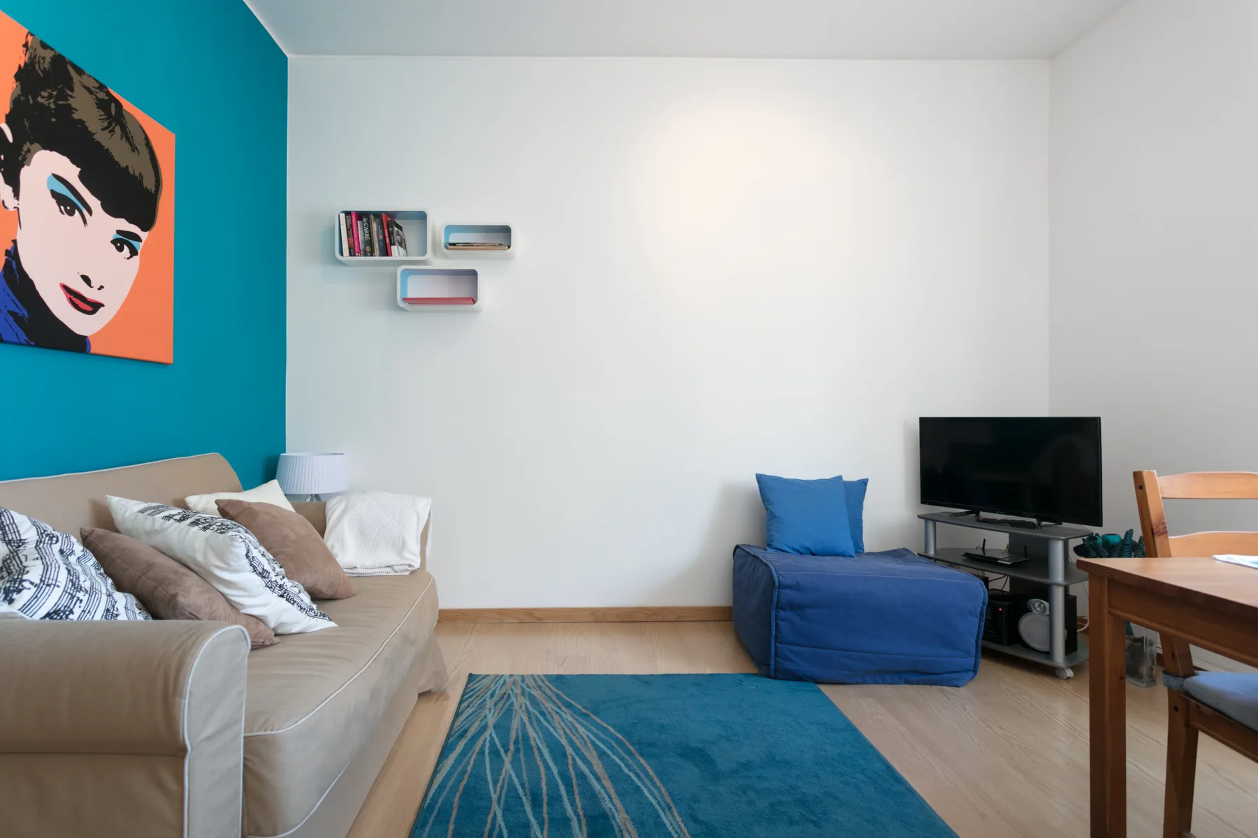 Sala de estar con sofá, pared azul y televisor.