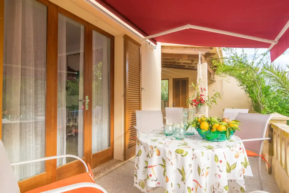 Un patio cubierto con una mesa de comedor y sillas junto a puertas de cristal.
