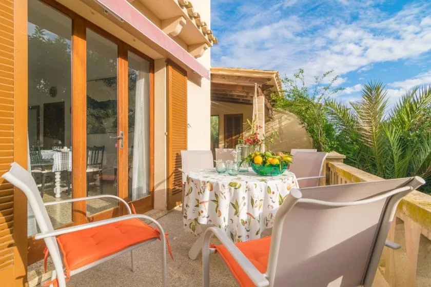 Una terraza soleada con mesa y asientos junto a puertas de vidrio.