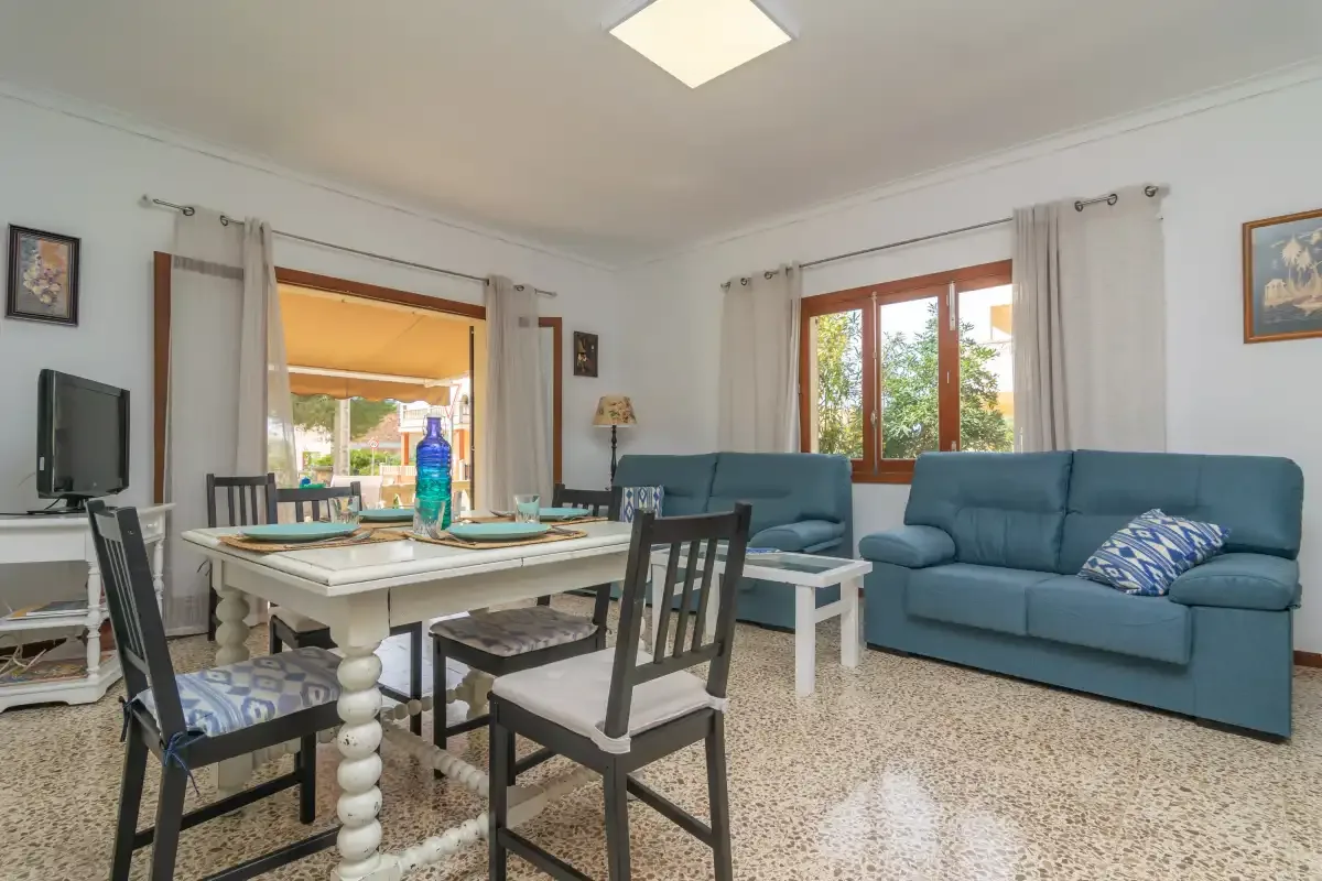 Sala de estar y comedor con asientos azules y una mesa junto a las ventanas.