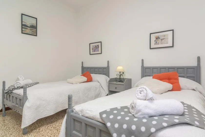 Un dormitorio luminoso con dos camas y cuadros en las paredes.