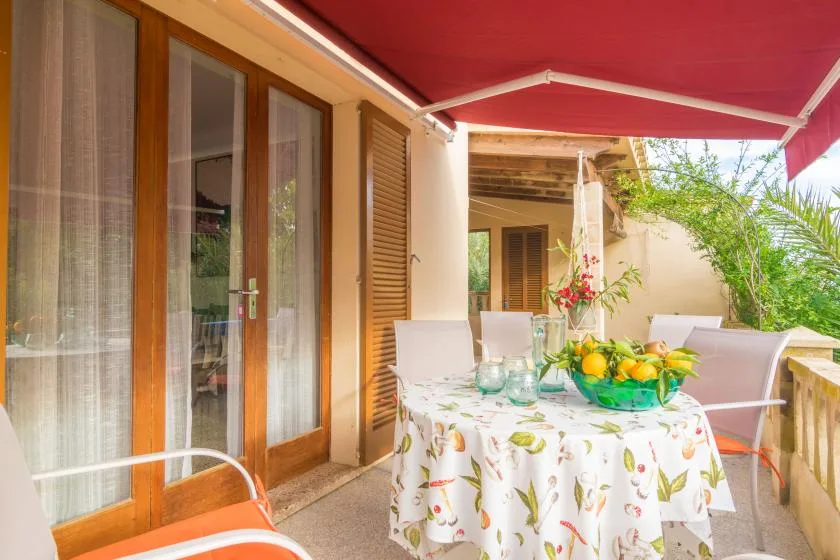 Una zona de comedor al aire libre con una mesa bajo un toldo rojo.