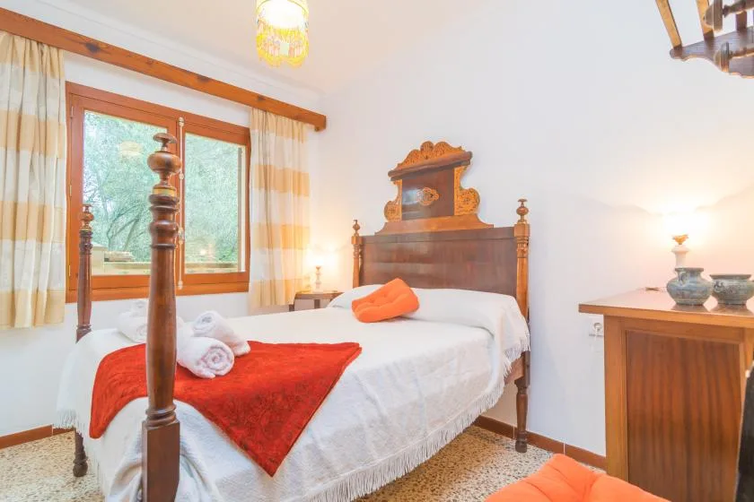 Un dormitorio con una cama de madera, ropa de cama blanca y una ventana con cortinas.