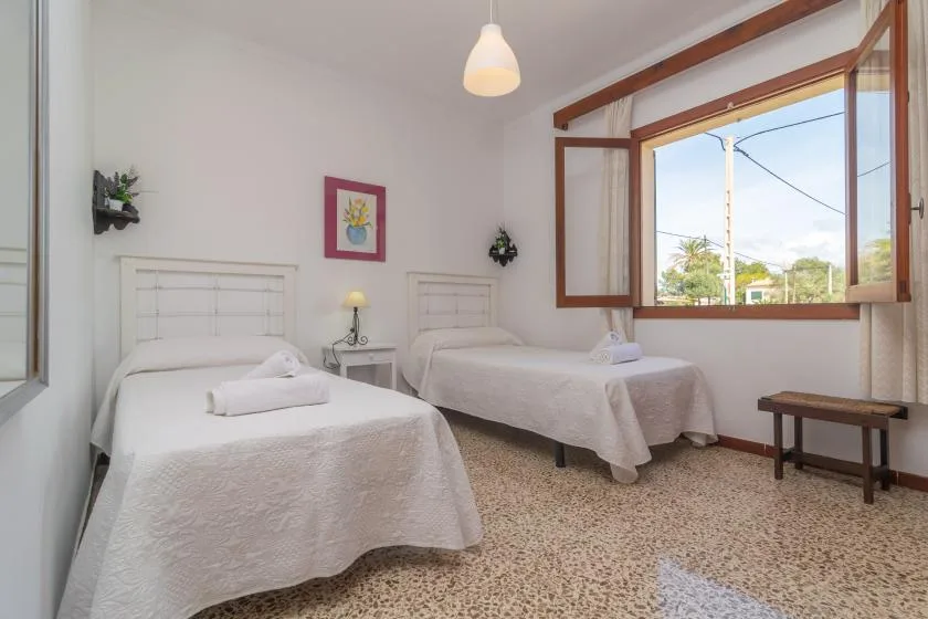 Un dormitorio con dos camas individuales y una ventana abierta con vistas a árboles.