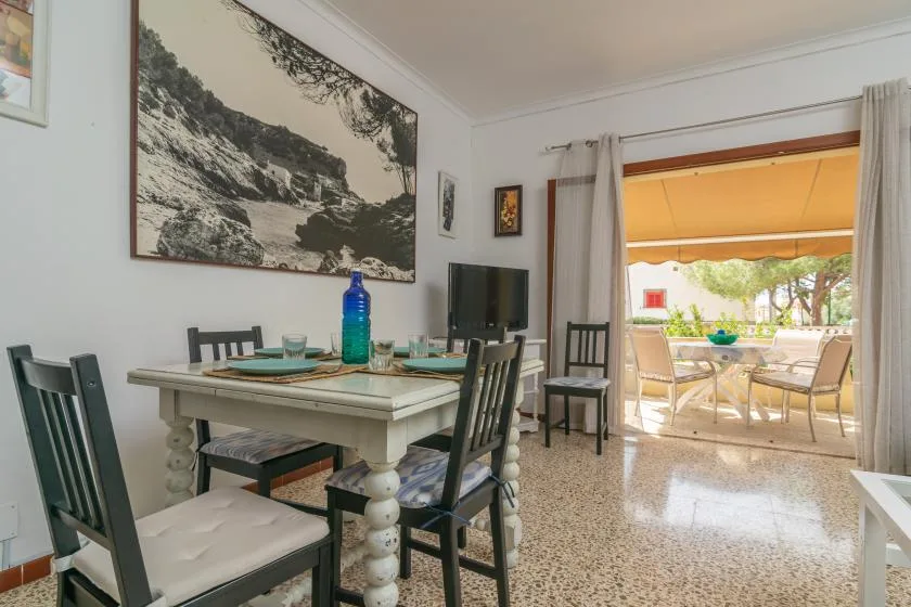 Comedor con una mesa puesta y una puerta abierta a un patio cubierto.