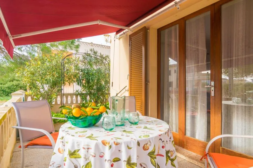 Comedor exterior cubierto con una mesa junto a puertas de vidrio.