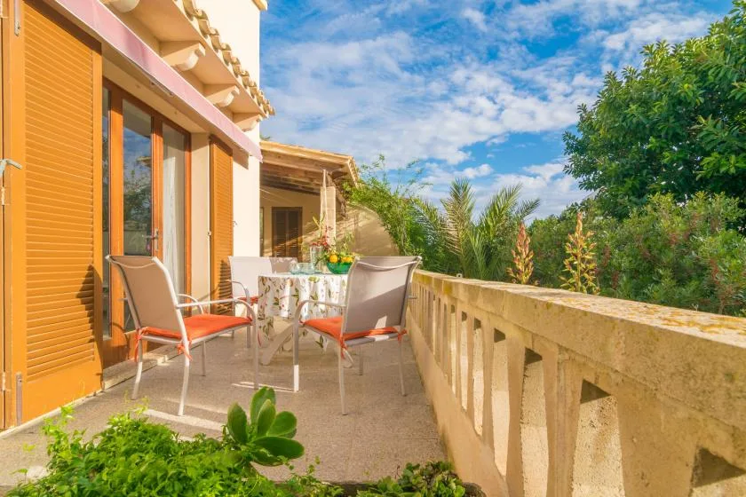 Una terraza exterior con asientos y una mesa junto a un edificio iluminado por el sol.