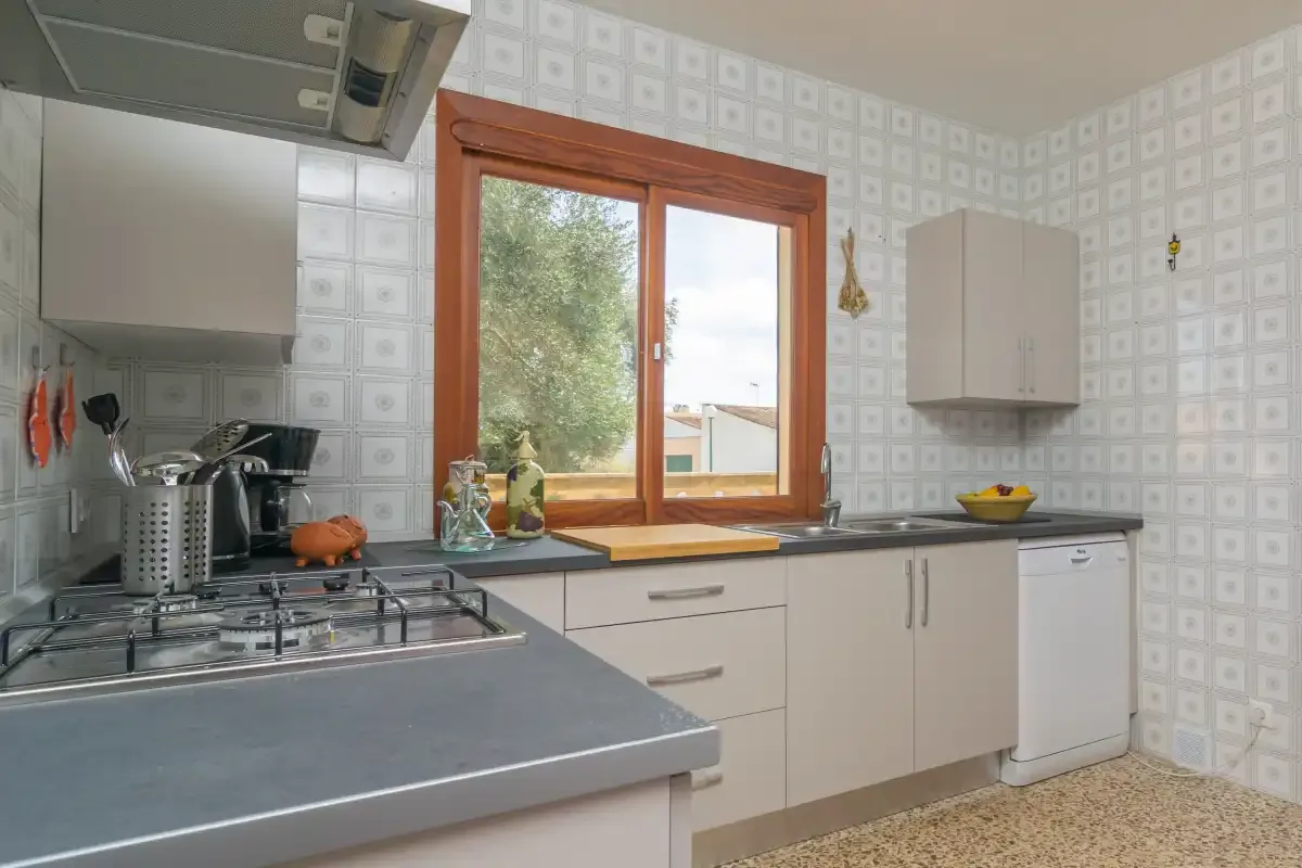 Una cocina con una placa de gas y una ventana sobre la encimera.