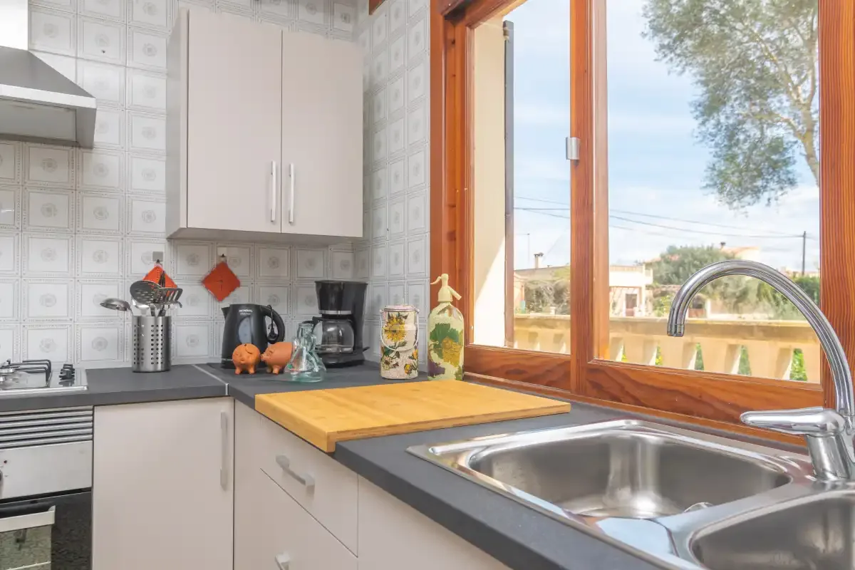 Una cocina luminosa con fregadero y encimera de madera junto a una ventana grande.