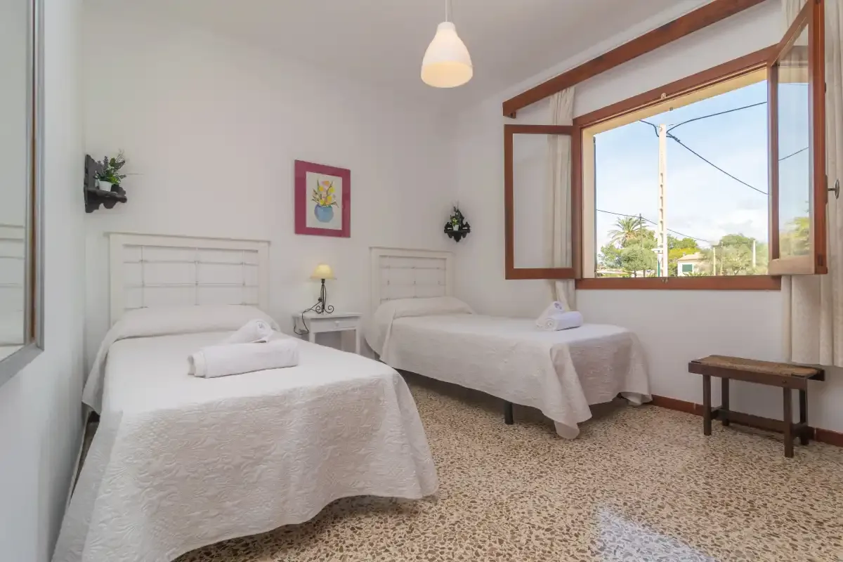 Dormitorio con dos camas individuales y una ventana abierta.