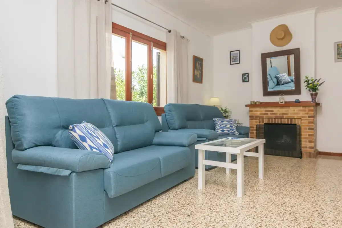 Una sala de estar con asientos azules, una mesa pequeña y una chimenea de ladrillo.