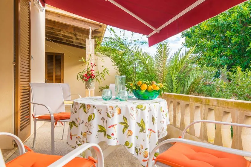 Una zona de comedor al aire libre tiene una mesa preparada con fruta y cristalería.