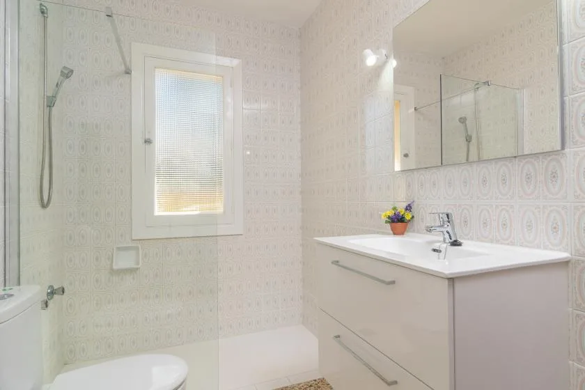 Un baño luminoso con lavabo, espejo y ducha.