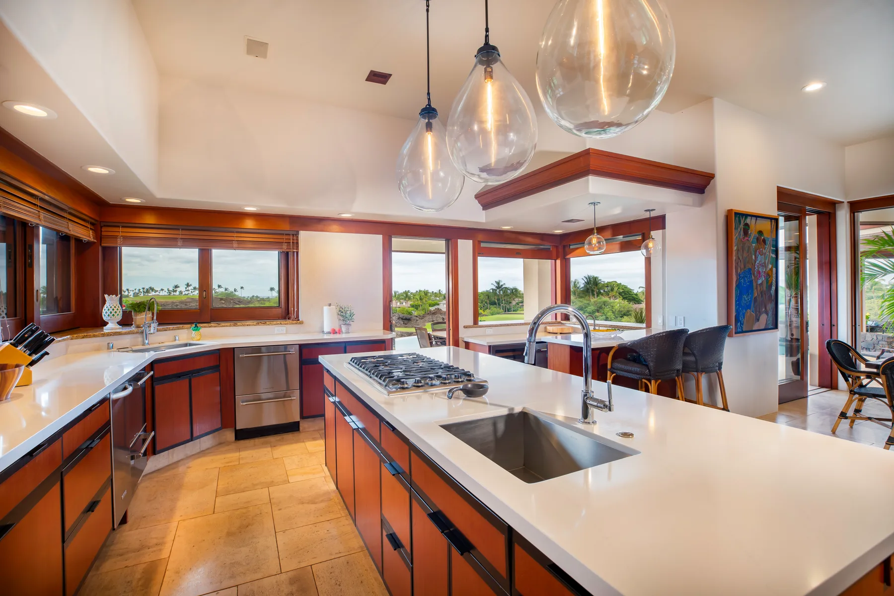 Una cocina amplia con una isla grande, fregadero y ventanas con vistas a la vegetación.