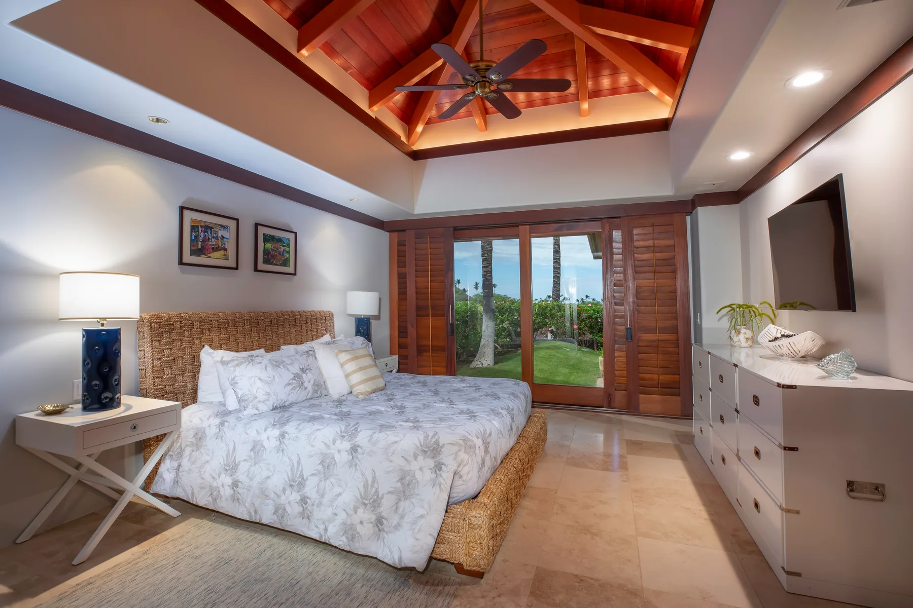 Un dormitorio con una cama bajo un techo abovedado de madera y un ventilador.