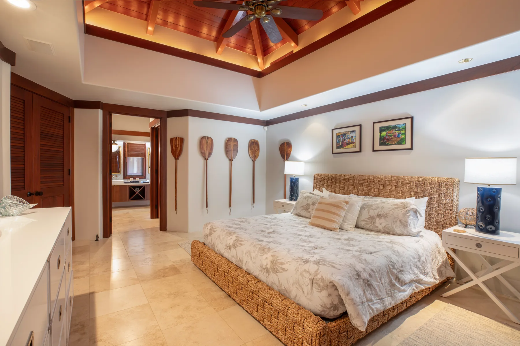 Un dormitorio con una cama tejida, ropa de cama clara y techo de madera expuesto.