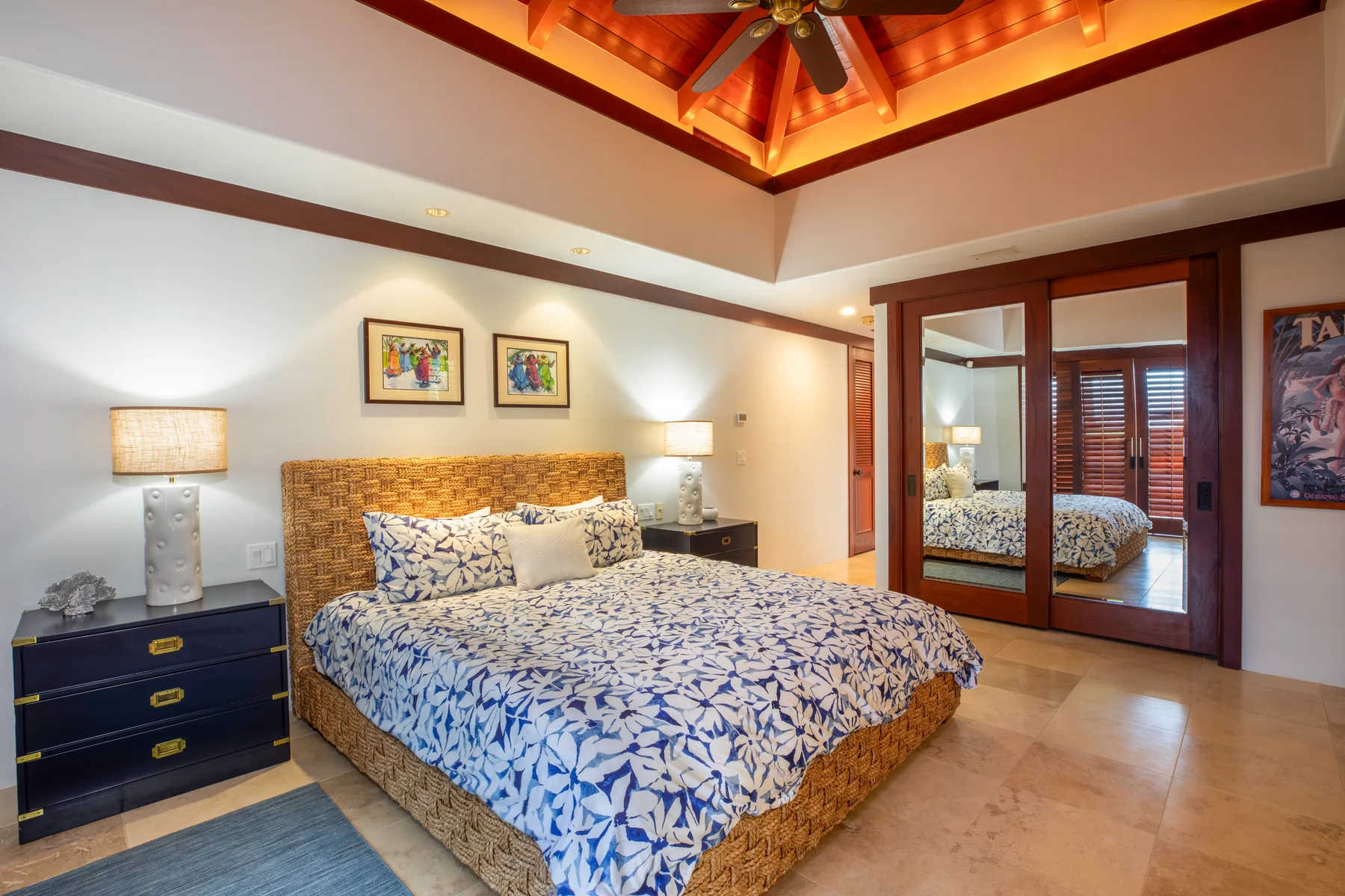 Un dormitorio con una colcha estampada y un techo decorativo de madera.