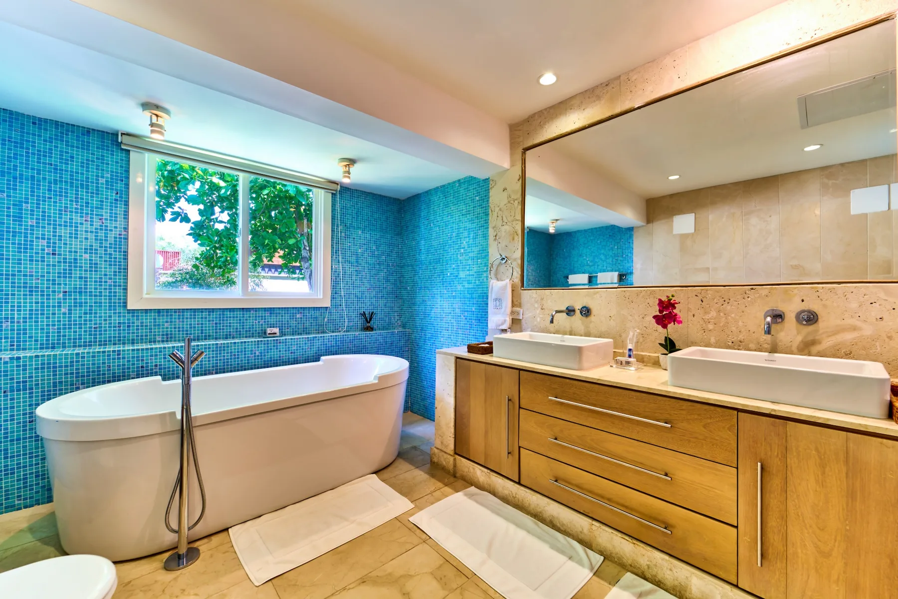 A bathroom with a bathtub, a double-sink vanity, and a large mirror.