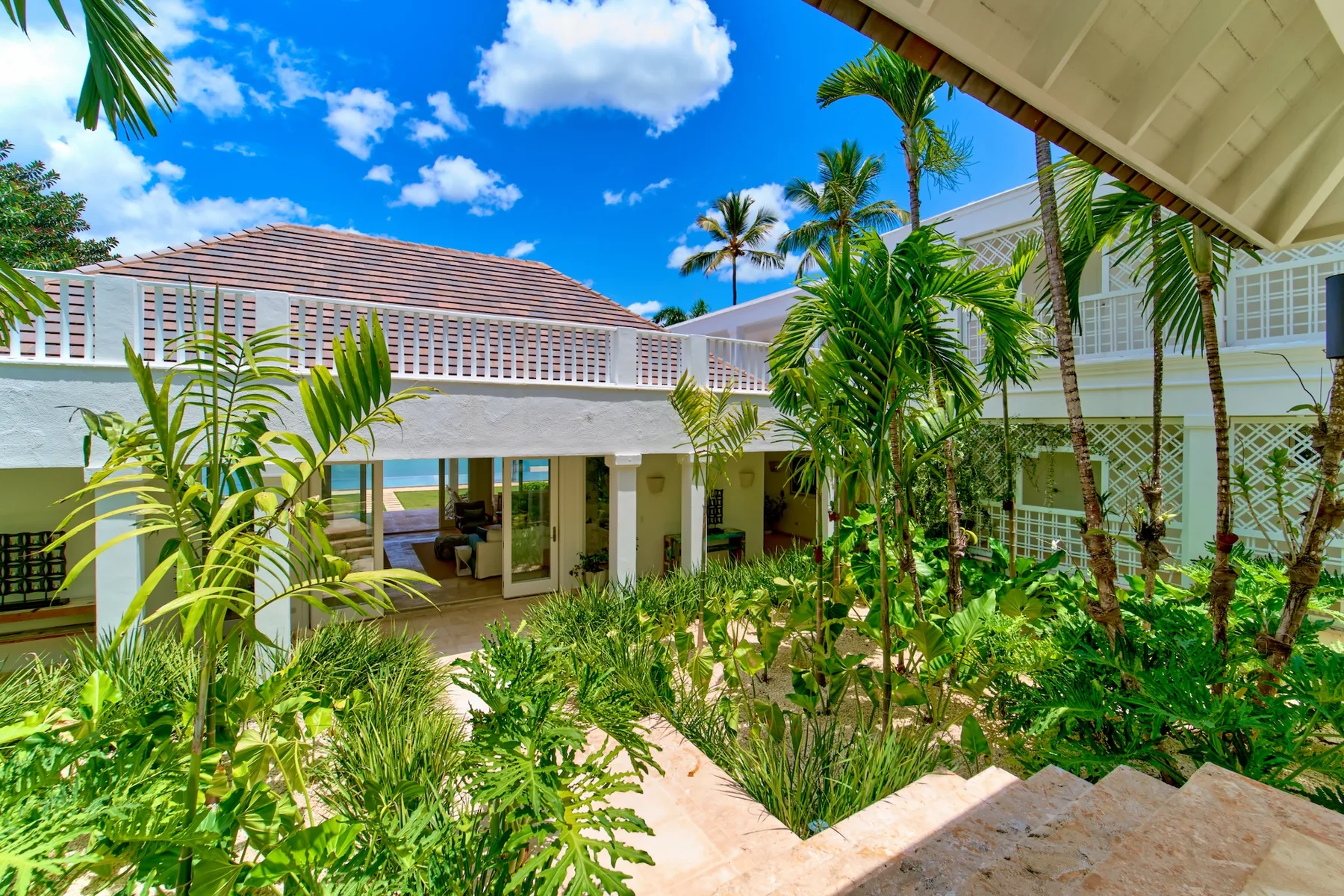 A tropical garden courtyard with a stone path and white buildings.