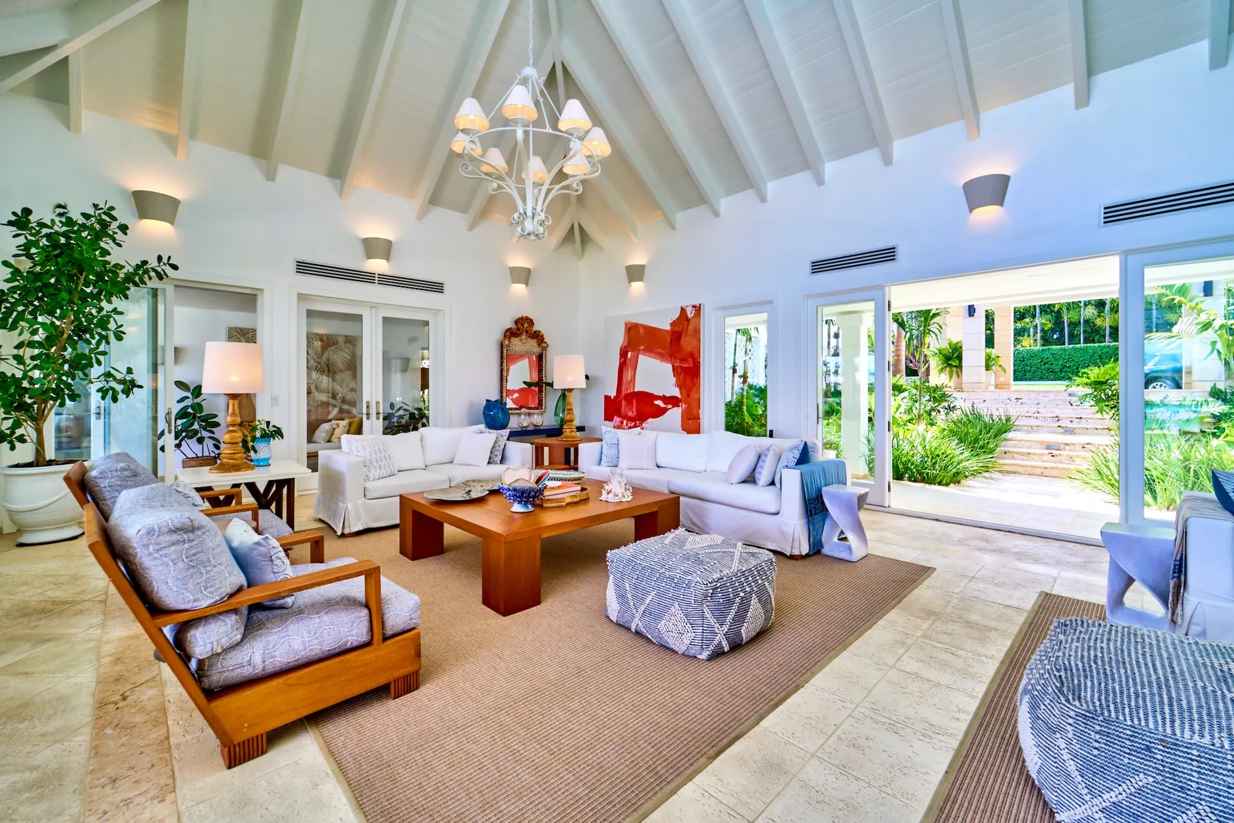 A bright living room with seating arranged around a coffee table beneath a vaulted ceiling.