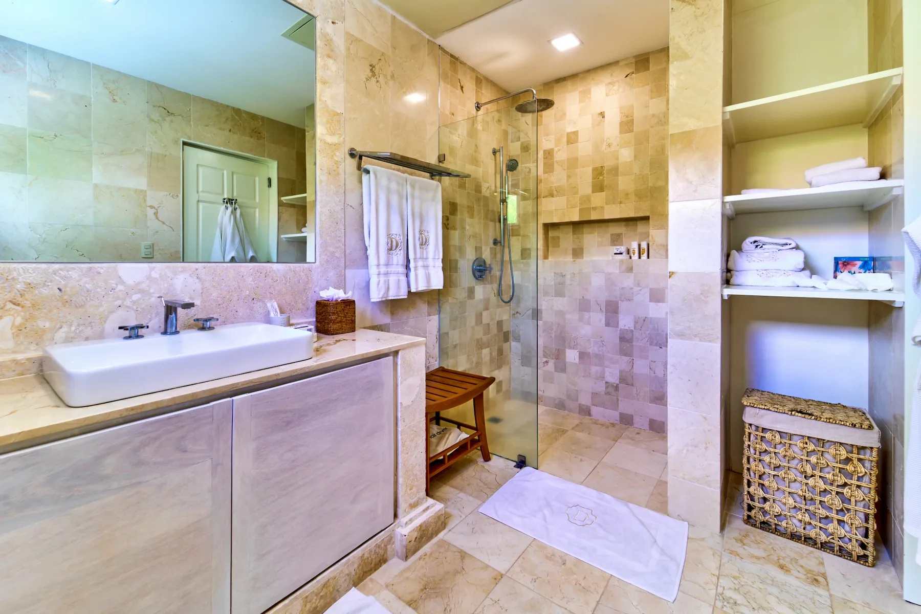 A bathroom with a vanity, a large mirror, and a glass shower.