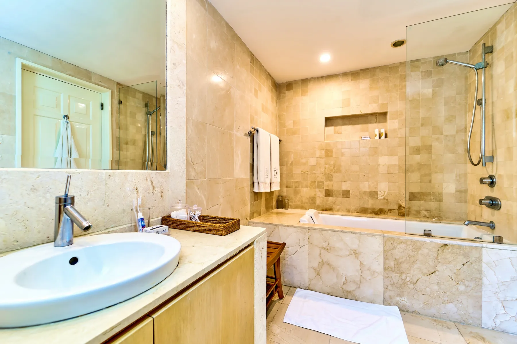 A bathroom with a sink, mirror, and bathtub with a shower.