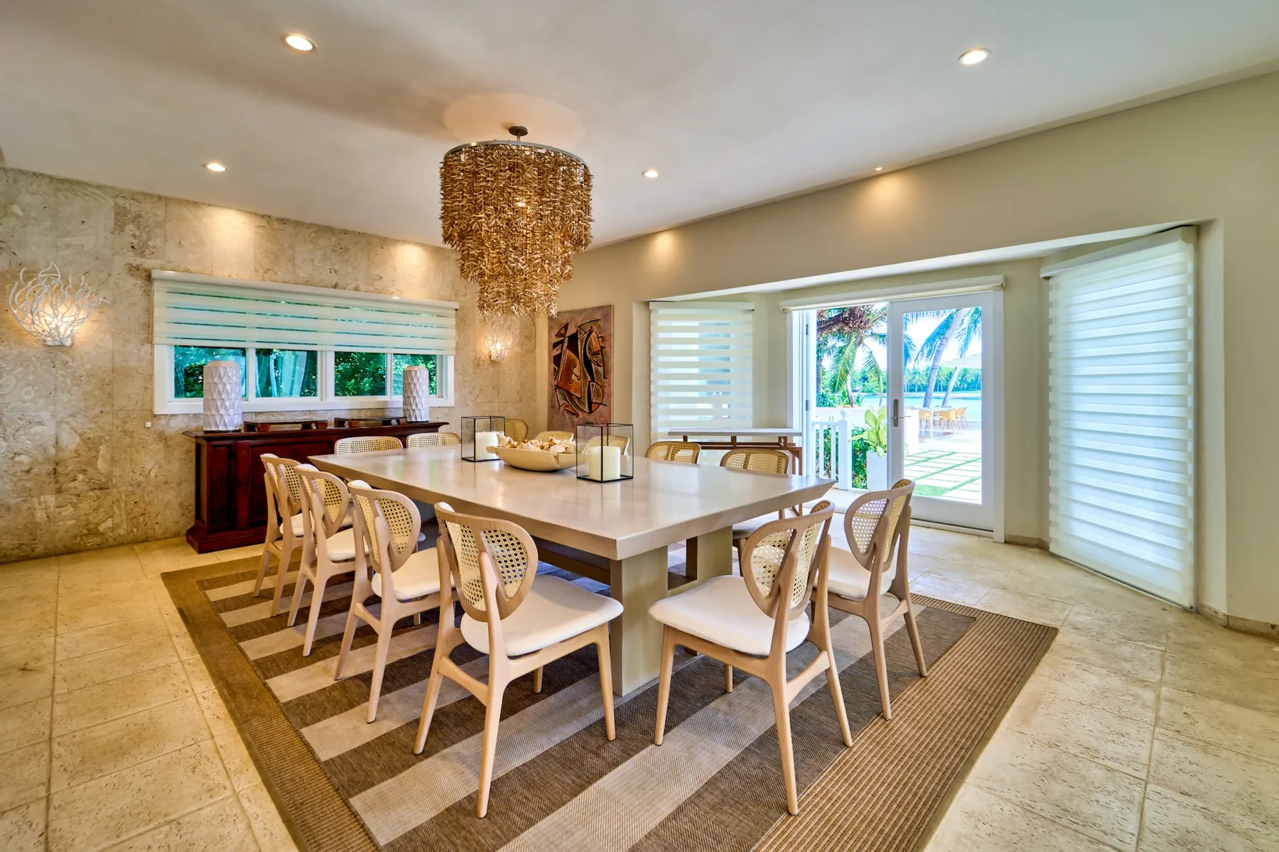 A dining room with a long table and chairs beneath a woven pendant light.
