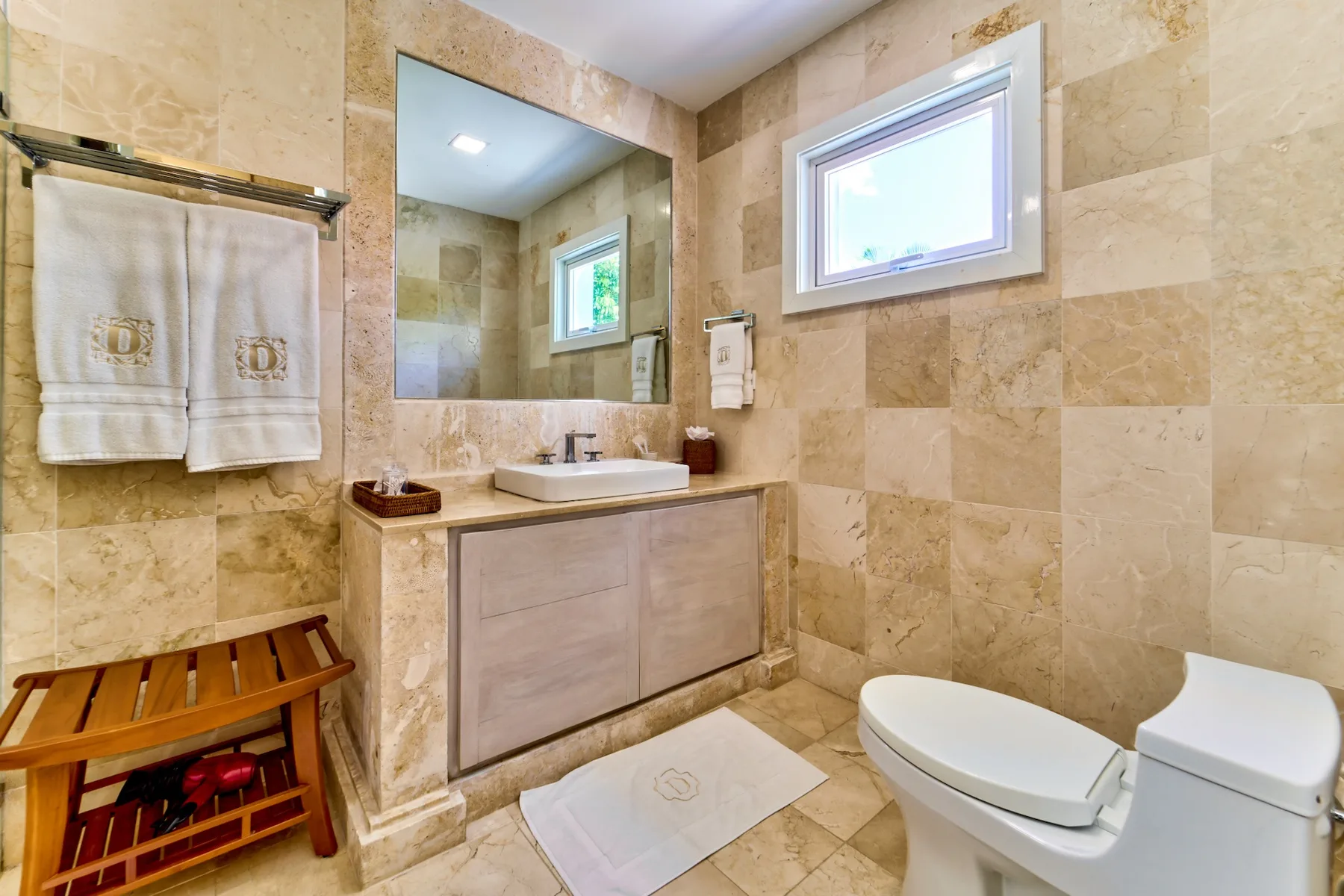 A tiled bathroom with a vanity, mirror, and toilet.