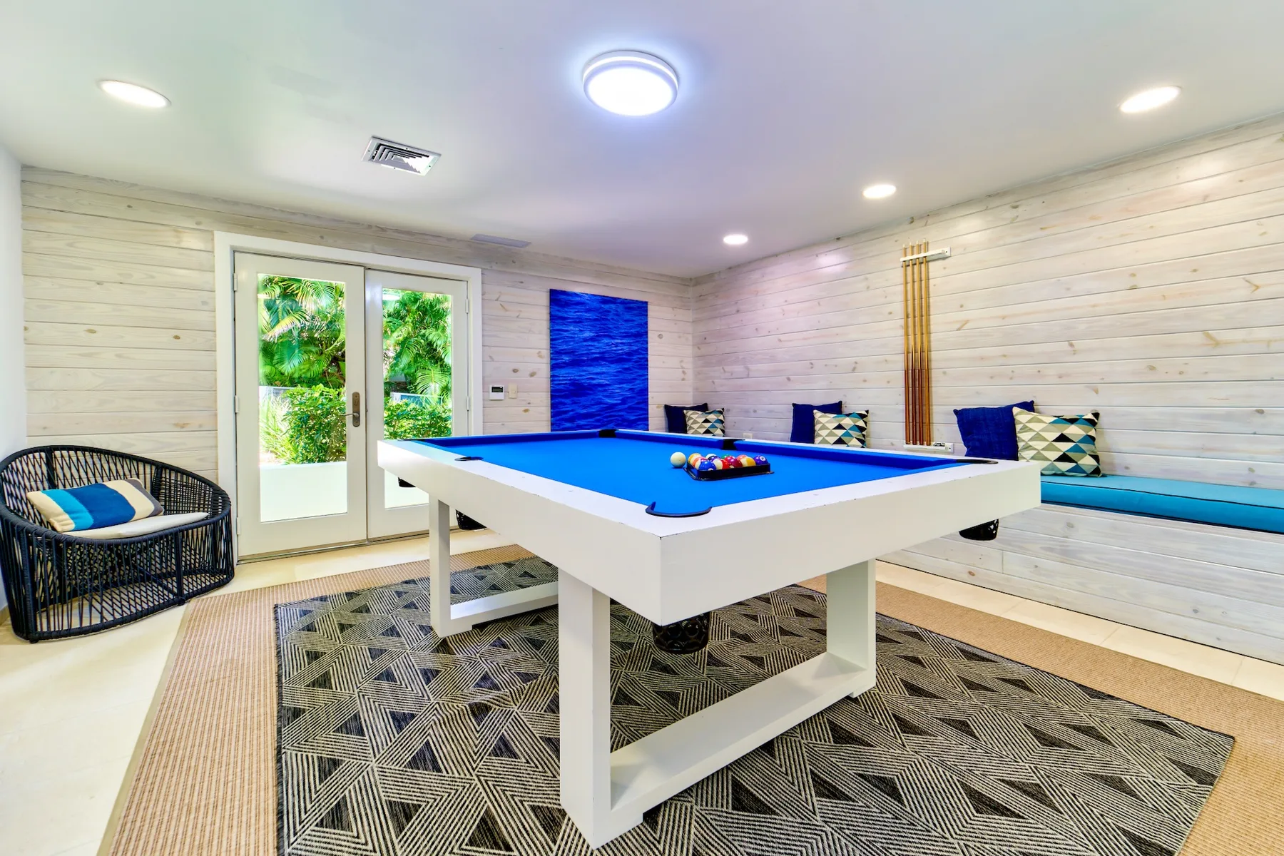 A game room with a blue pool table and seating along the walls.